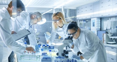 Team of Medical Research Scientists Work on a New Generation Disease Cure. They use Microscope, Test Tubes, Micropipette and Writing Down Analysis Results. Laboratory Looks Busy, Bright and Modern.